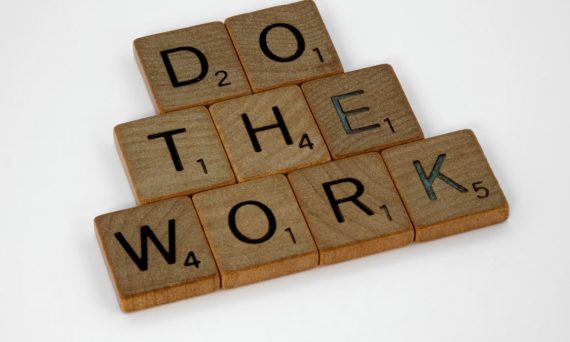 Creative arrangement of Scrabble tiles spelling 'Do the Work' on a white background.